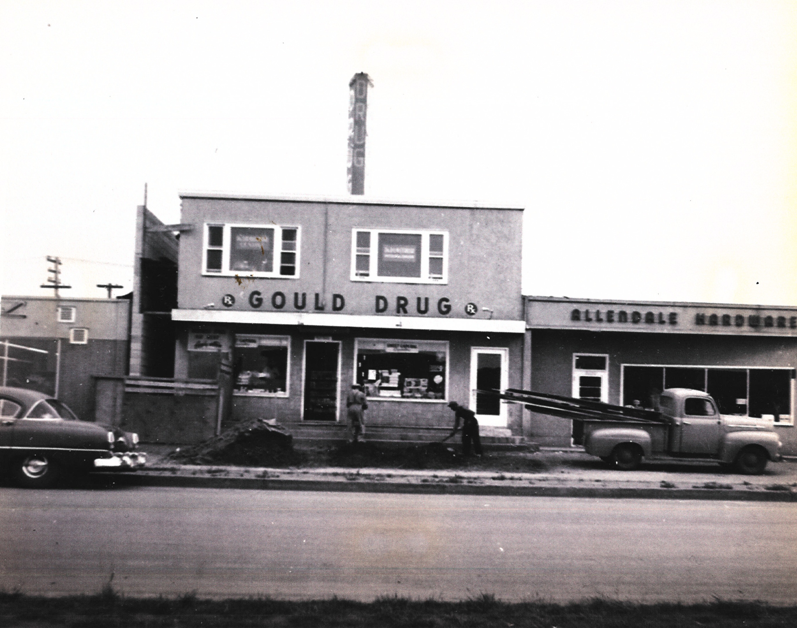Gould Drug and Allendale Hardware shortly after opening, with a car and truck out front