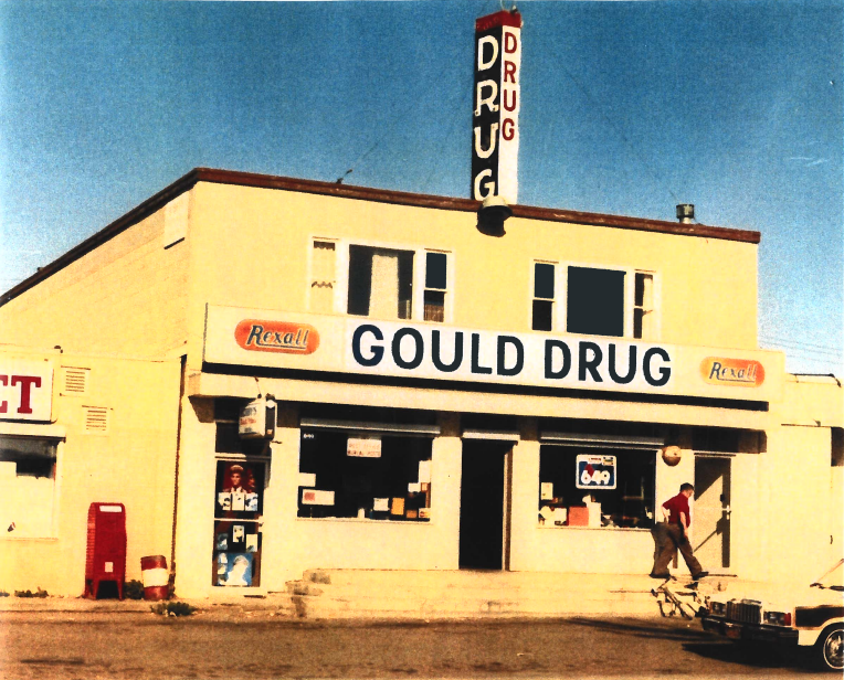 Gould Drug storefront with a child riding by on a bike, 1980s